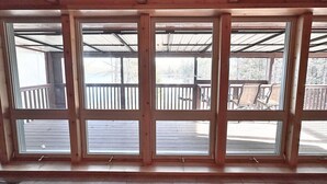 Ein Zimmer mit großen Fenstern, Holzbalken und Blick auf eine Terrasse.