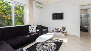 A modern living room with a black sofa, a white coffee table, and a large window with curtains. - Villa Casa Mia in Dalyan (Ortaca)