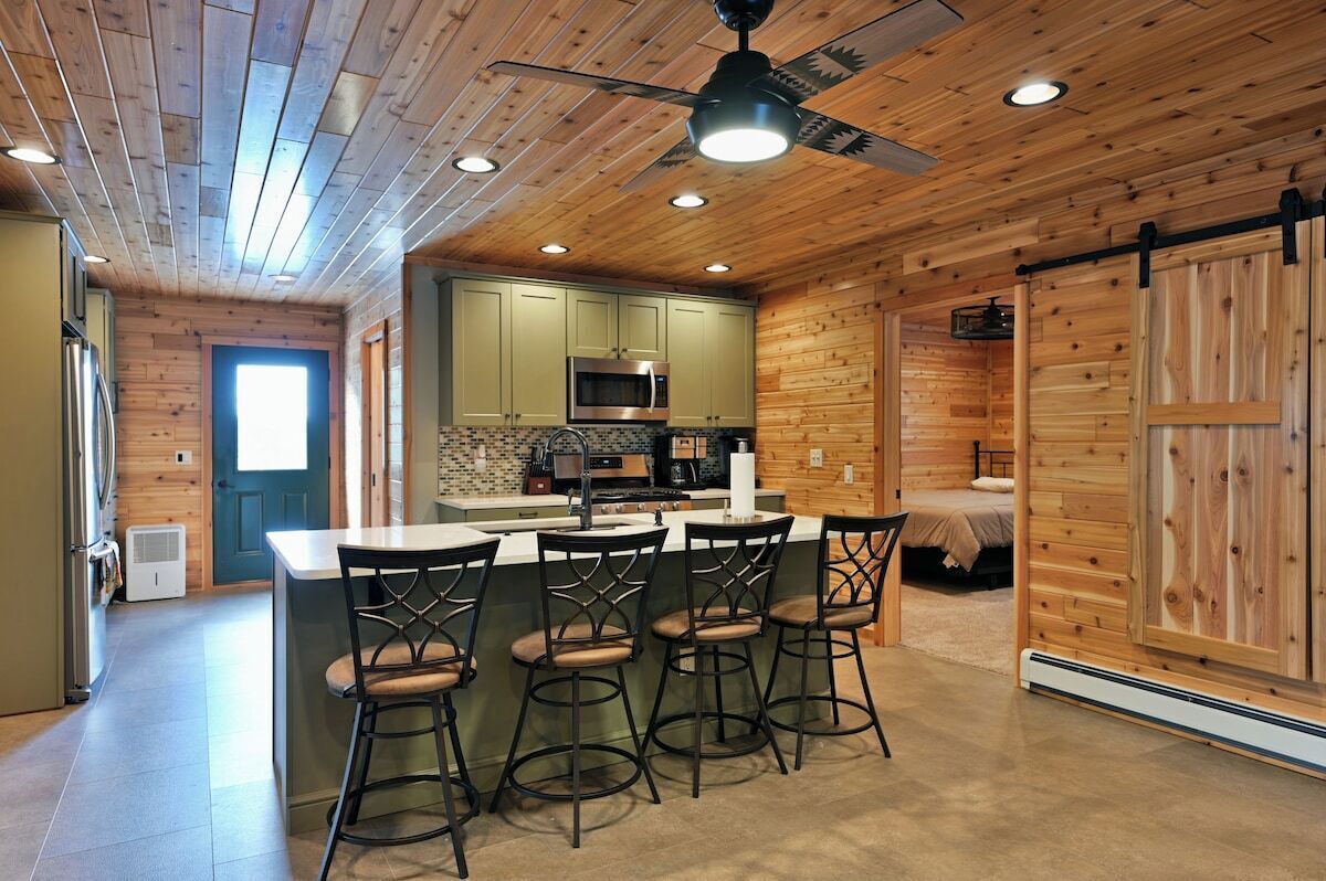 Una cocina moderna con una isla central, taburetes de bar y un ventilador de techo.