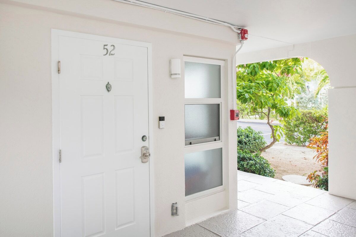 A white door with the number 52, a glass door with a frosted panel, and a fire alarm on the wall.