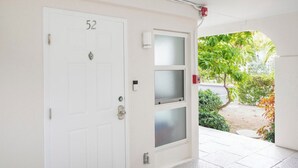 Una porta blanca amb el número 52, una porta de vidre amb un panell opac, i un detector de fum a la paret.