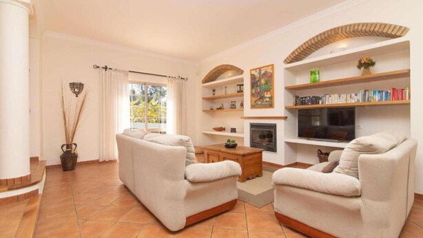 A living room with two beige sofas, a wooden coffee table, a fireplace, and bookshelves.