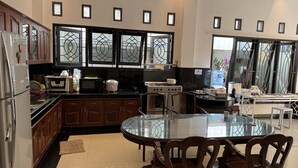 A modern kitchen with wooden cabinets, a glass dining table, and a stove.