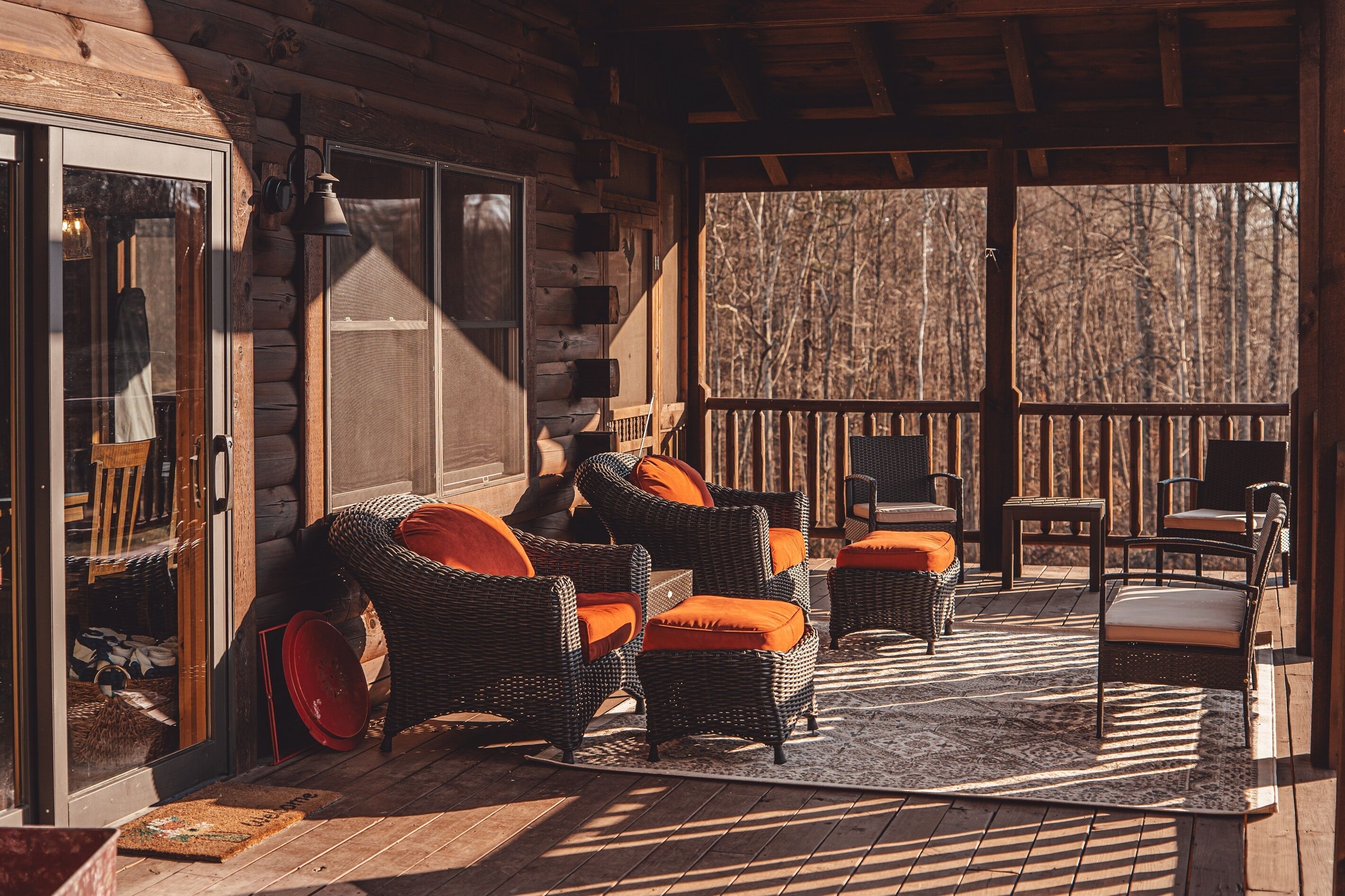 Une cabane en rondins avec des meubles en osier et une terrasse en bois.