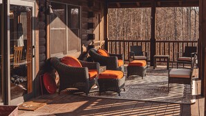 Una cabaña de troncos con mobiliario de mimbre y una terraza de madera.