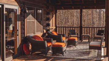 Une cabane en rondins avec des meubles en osier et une terrasse en bois.