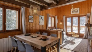 A wooden interior with a dining table, chairs, and a kitchen area.