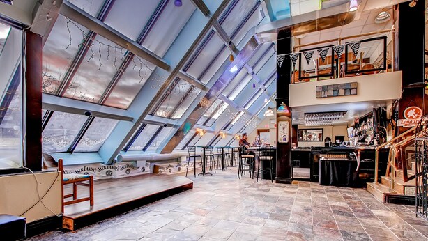 A spacious interior with a high ceiling, skylights, a bar area, and a seating area with a view of the sky. - Mt Green 3-F04 | Studio Condo (Killington)
