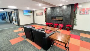 A conference room with a large table, several chairs, and a fireplace with red flowers. - Mt Green 3-F04 | Studio Condo (Killington)