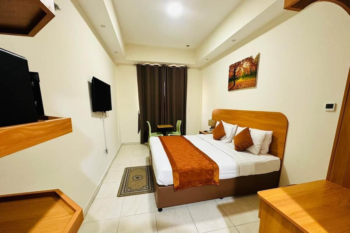 Une chambre d’hôtel avec un lit, une télévision, un bureau et une chaise.