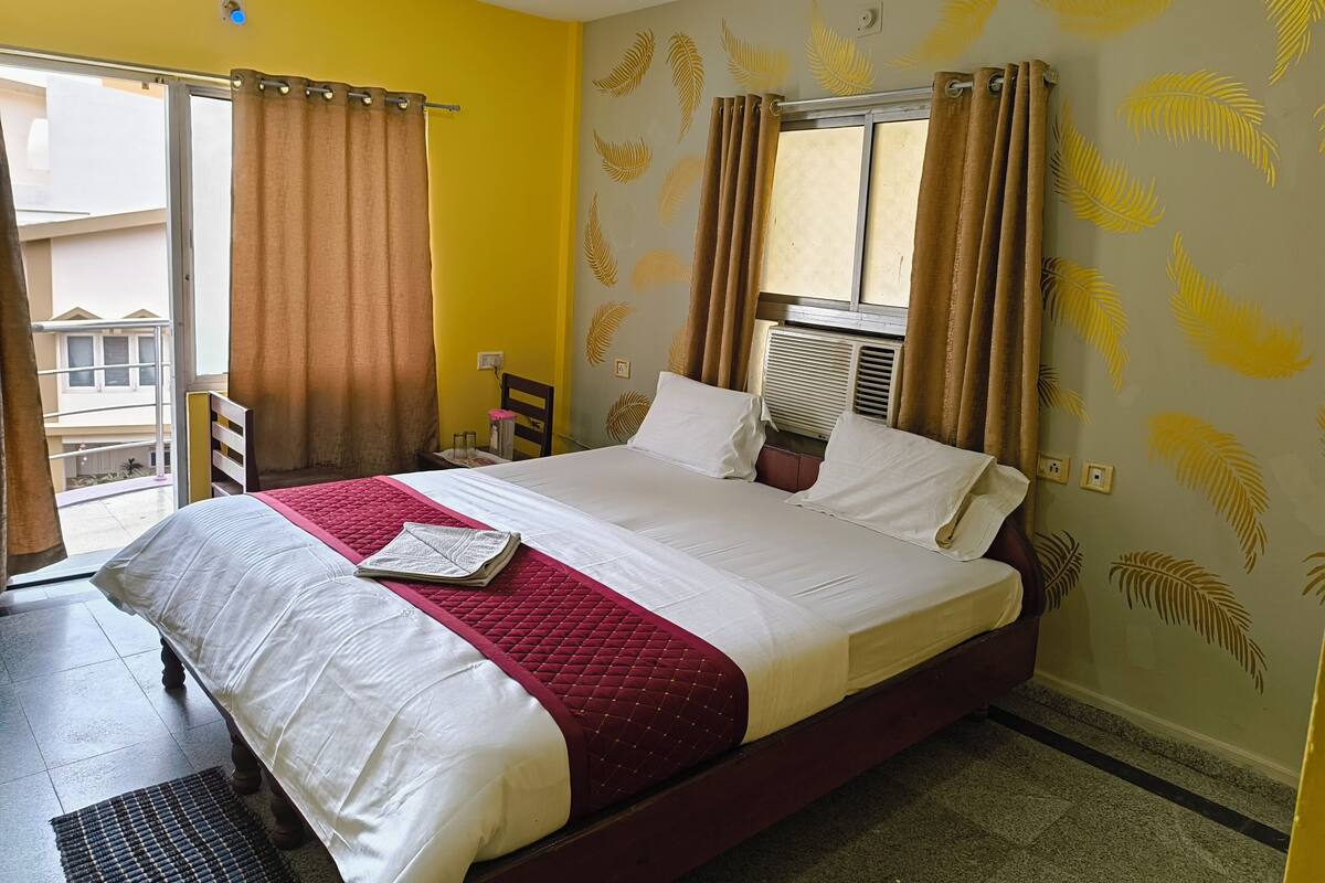 Habitación de hotel con cama, cortinas, una ventana y una pared con diseño de hojas.