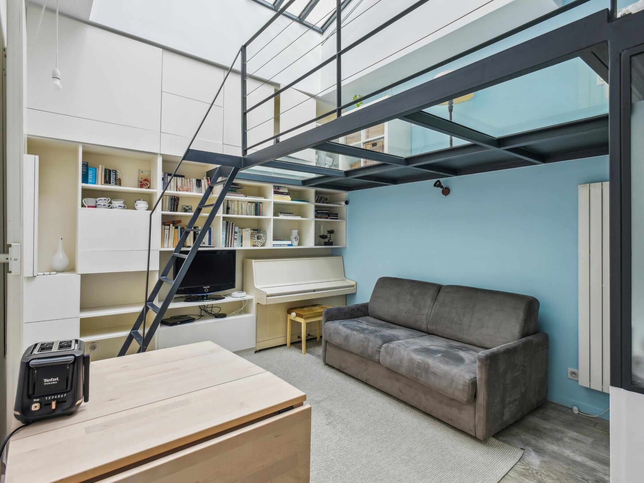A modern living room with a sofa, a TV, a bookshelf, and a desk.