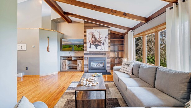 A spacious living room with a fireplace, wooden beams, a sofa, and a television.