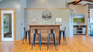 A bar area with a wooden counter, two stools, and a wall-mounted sign indicating ski lift and patrol services.