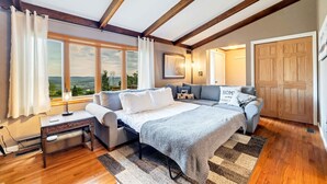 A bedroom with a bed, a sofa, a desk, and a window with curtains.