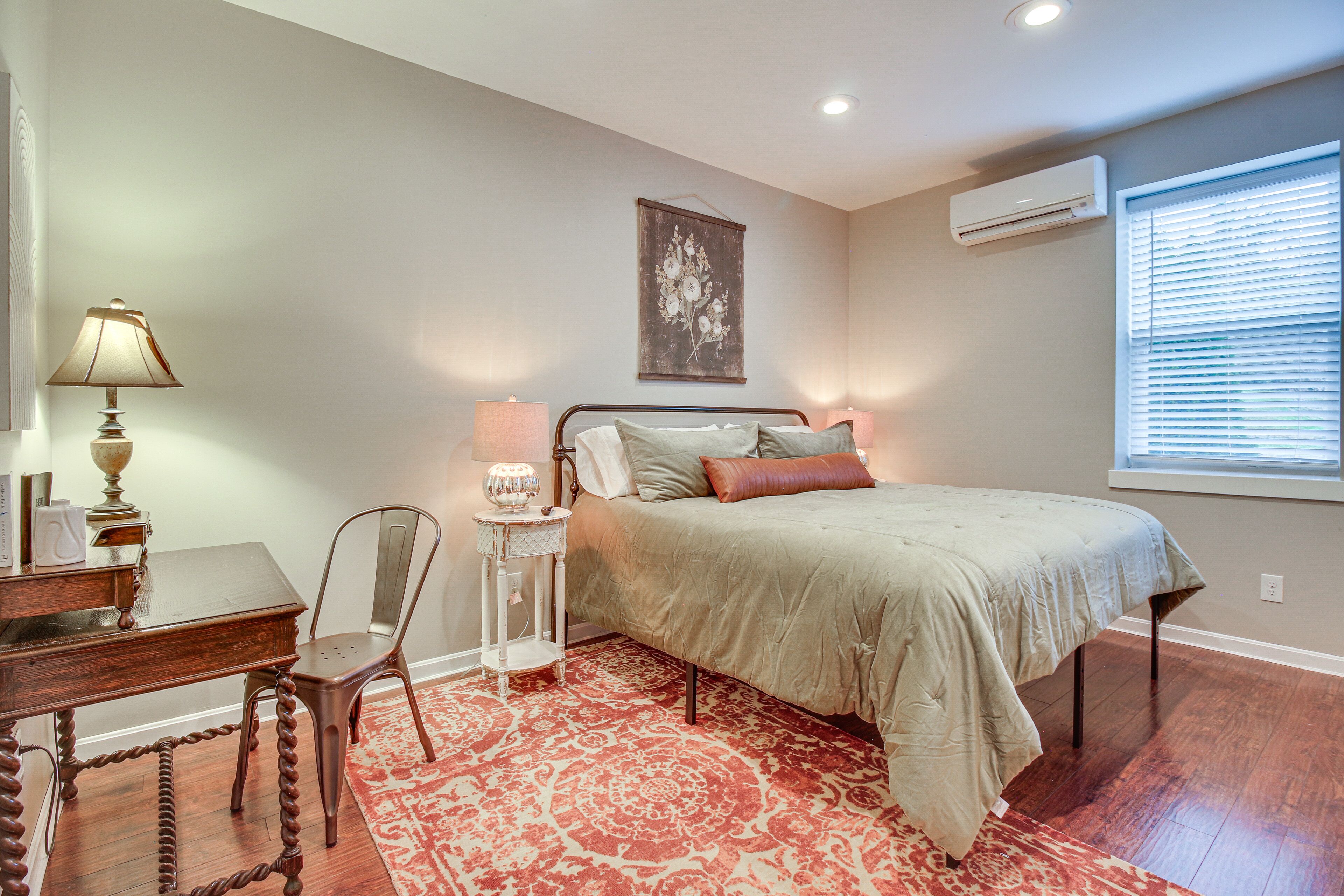 A bedroom with a bed, bedside lamps, a desk, and a chair.