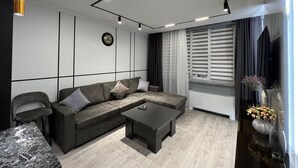 Un salon moderne avec un canapé d’angle, une table basse et un téléviseur.