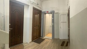 Un couloir avec deux portes en bois, un ascenseur et une porte blanche.