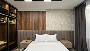 Une chambre d’hôtel moderne avec un grand lit, une armoire en bois et un mur décoratif en pierre.