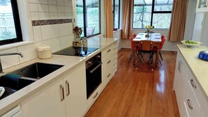 Una cocina moderna con armarios blancos, una estufa negra y un comedor con mesa y sillas.