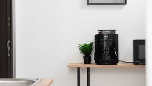 Una cocina con cafetera, una pequeña planta en maceta y microondas sobre una encimera de madera.