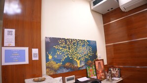 Un mostrador de recepción con un cuadro de un árbol, un cartel con los horarios de registro y un código QR.