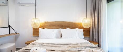 A modern hotel room with a large bed, two bedside lamps, a wooden headboard, and a large window with curtains.
