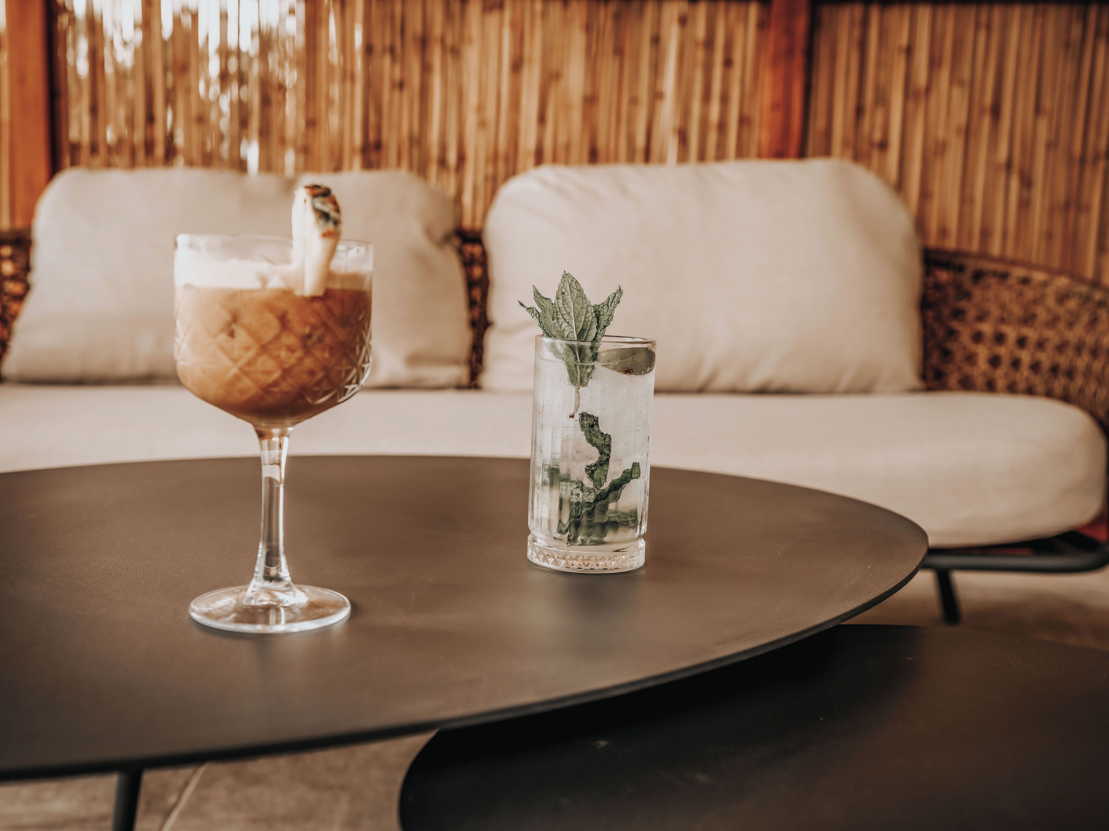 A table with a glass of iced coffee and a glass of water with mint leaves.