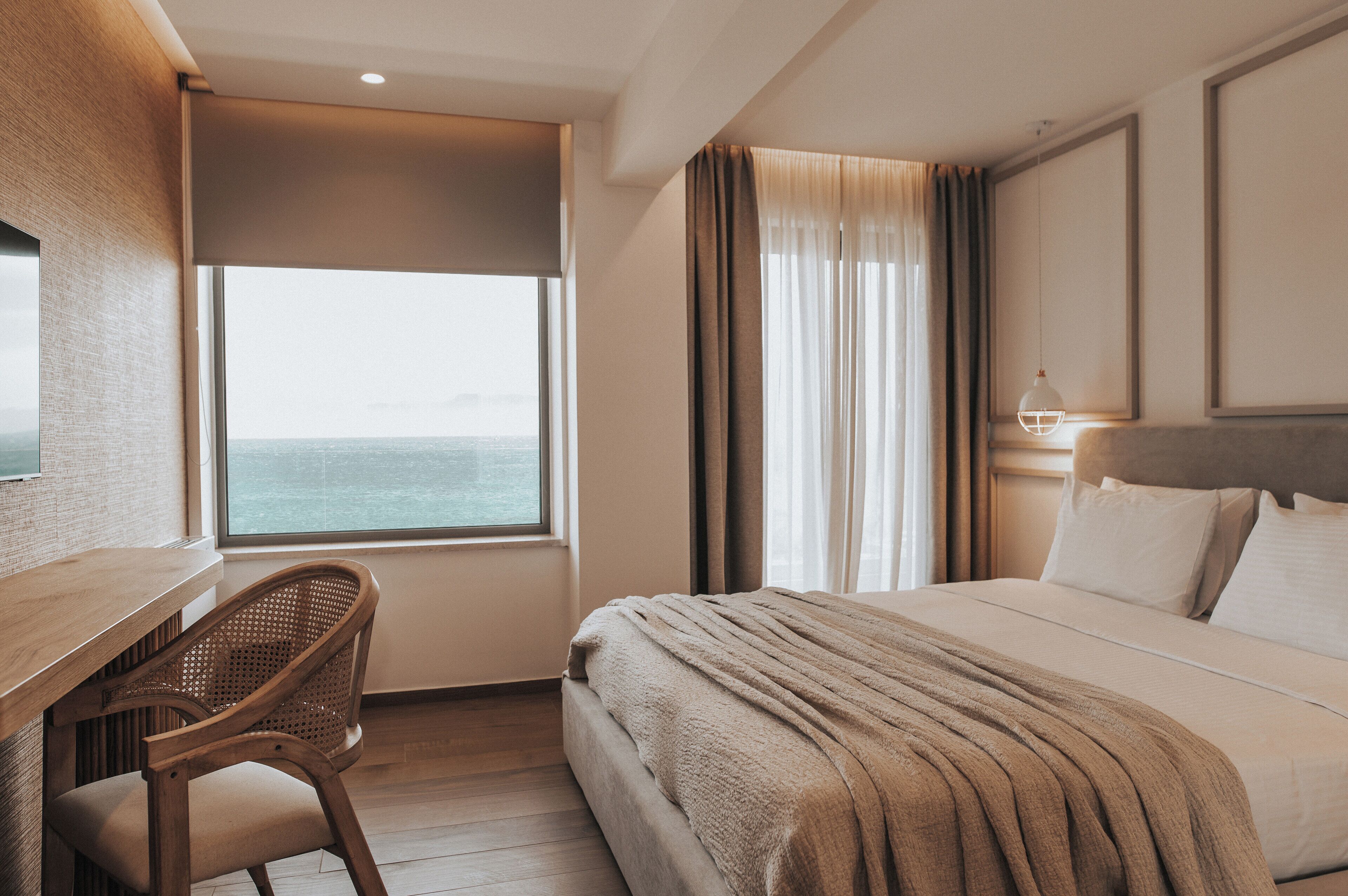 A hotel room with a large bed, a desk, and a chair.