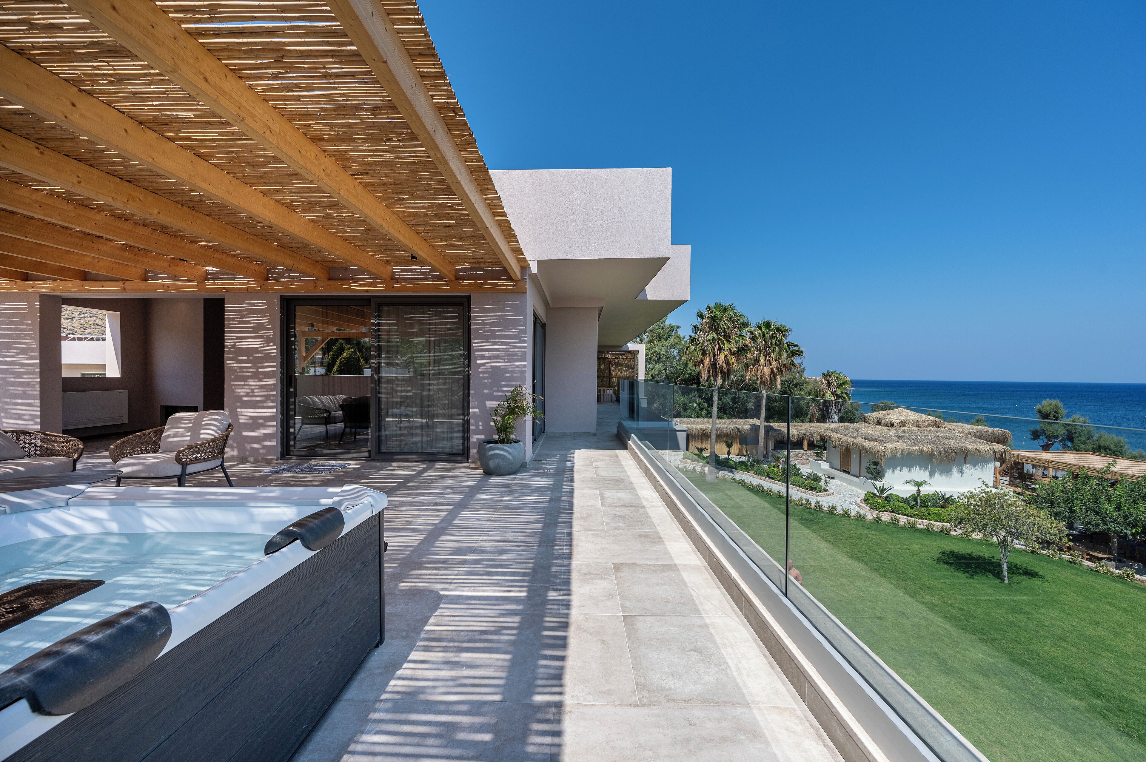 A modern outdoor area with a hot tub, seating, and a view of the ocean.