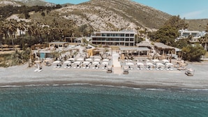 A beachside resort with multiple lounge areas, a pool, and a mountain backdrop. - Sagredo Beachfront Retreat & Spa by E-GEO (Kos)