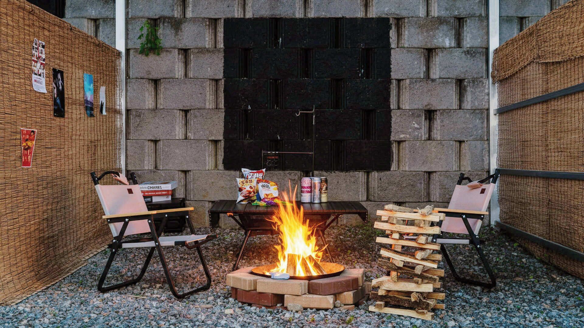 An outdoor seating area with a fire pit, chairs, and a table with snacks.