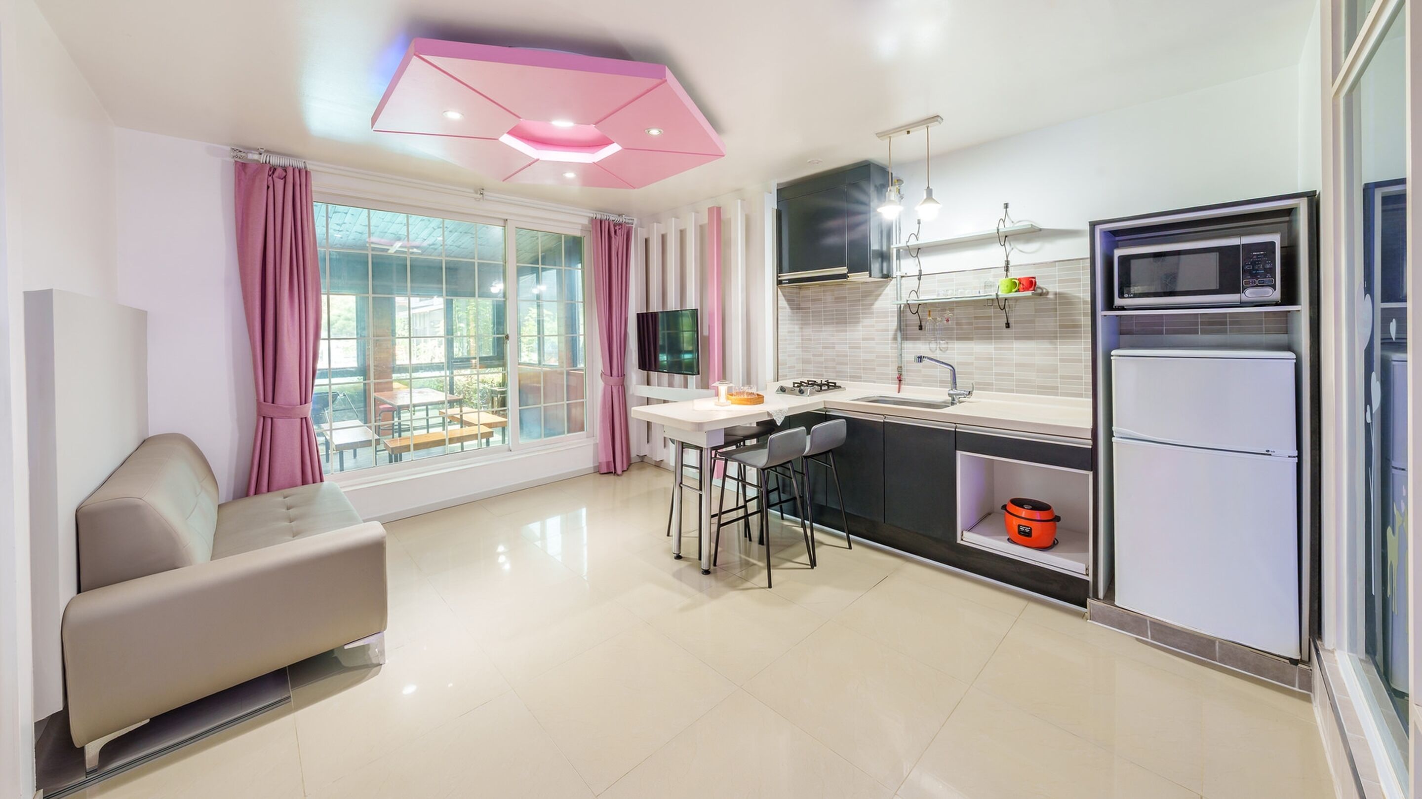 A modern kitchen with a dining area, a sofa, and a TV.