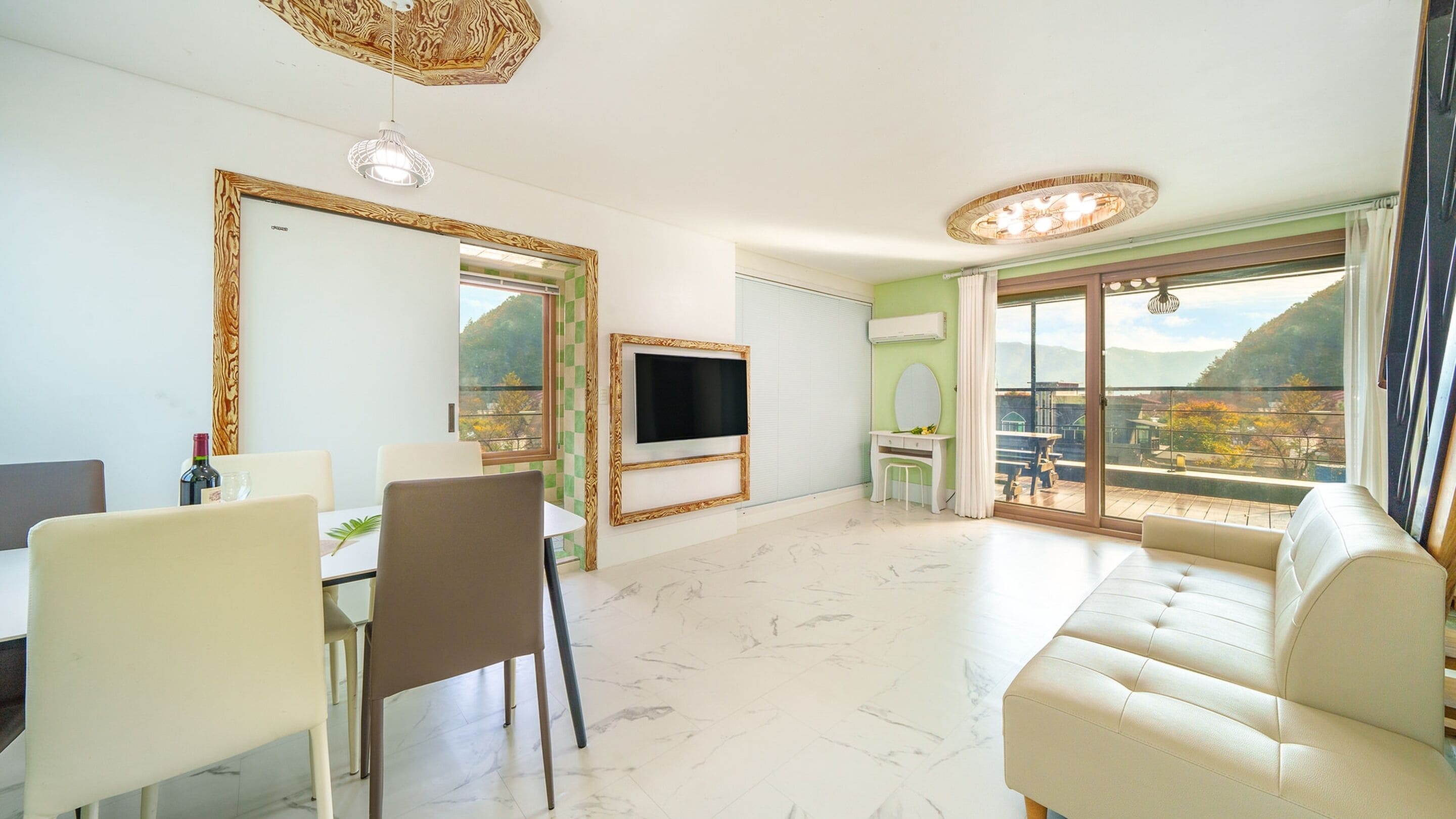 A modern living room with a large window, a flat-screen TV, a sofa, and a dining area with chairs and a table.