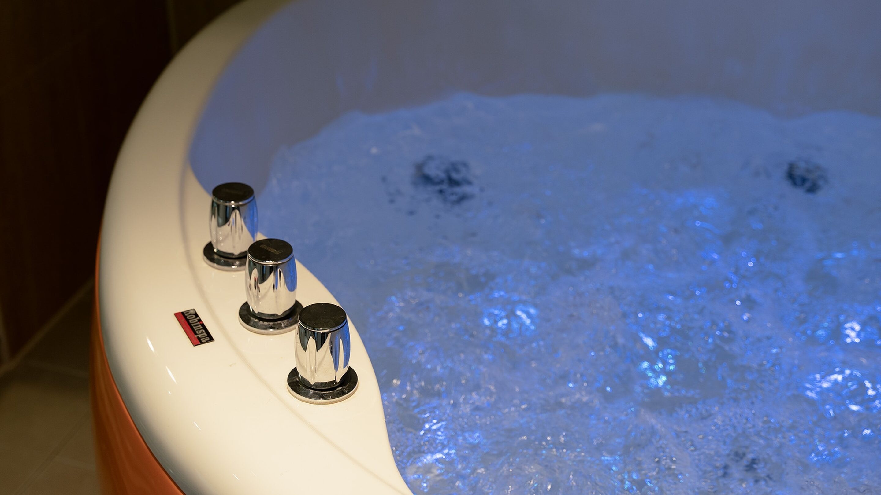 A bathtub with three control knobs and a visible brand label.