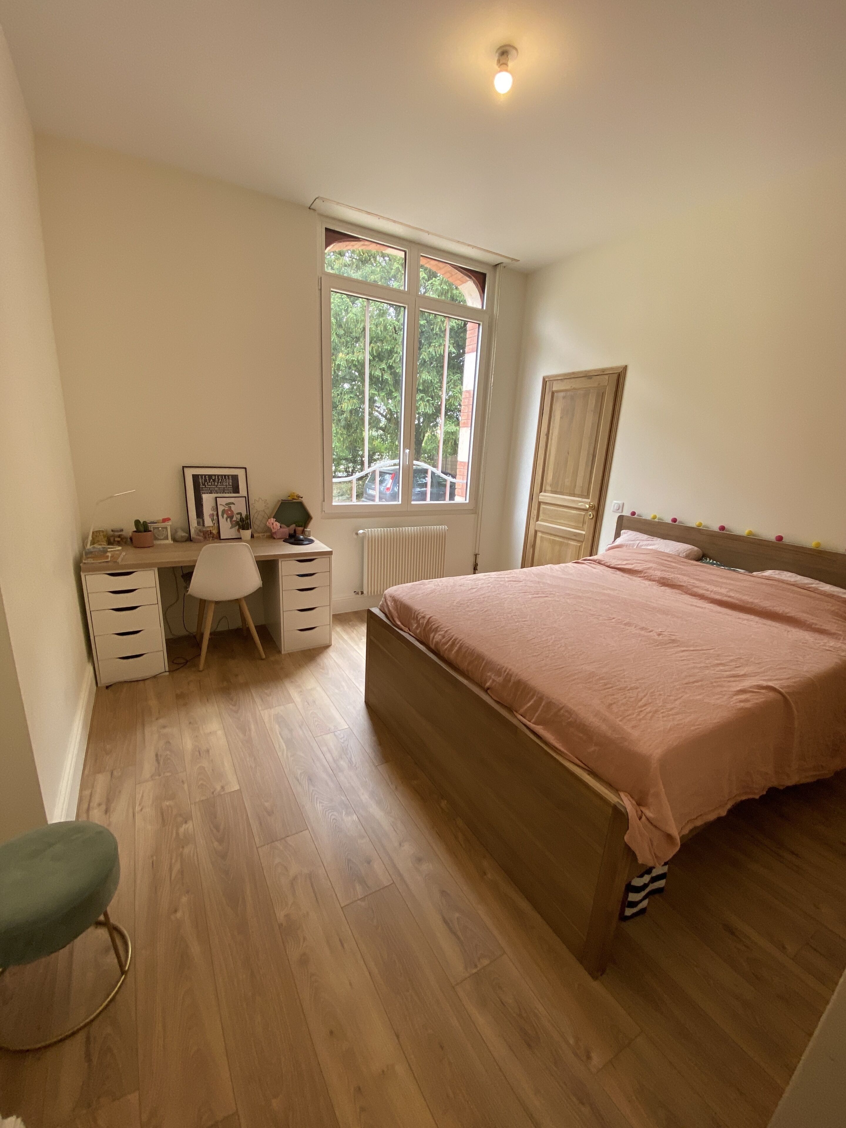 A bedroom with a bed, a desk, a chair, and a window.