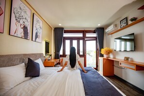 Een hotelkamer met een bed, bureau, televisie en grote ramen.