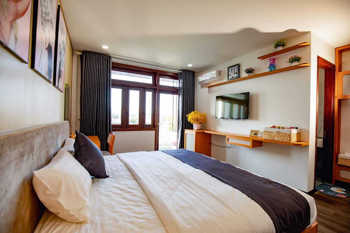 Une chambre d’hôtel avec un lit, un bureau, une télévision et une fenêtre avec des rideaux.