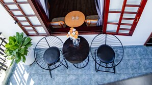 A rooftop terrace with a wooden table and chairs, a potted plant, and a view of the interior.