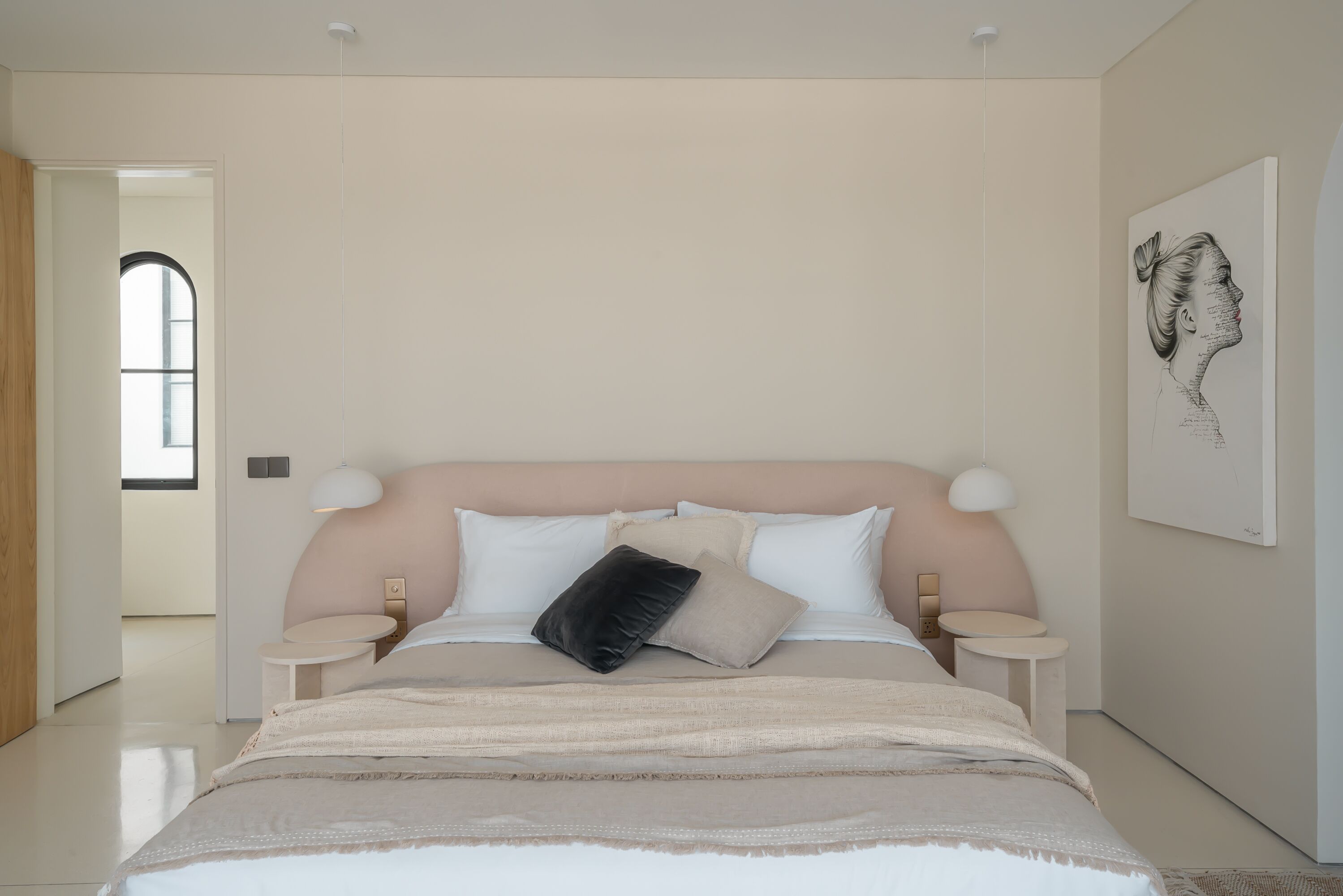A modern bedroom with a large bed, bedside tables, and a window.