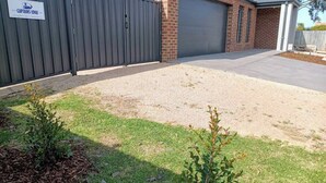 A residential property with a brick garage, a gravel driveway, and a metal gate. - Captains Edge (Paynesville)