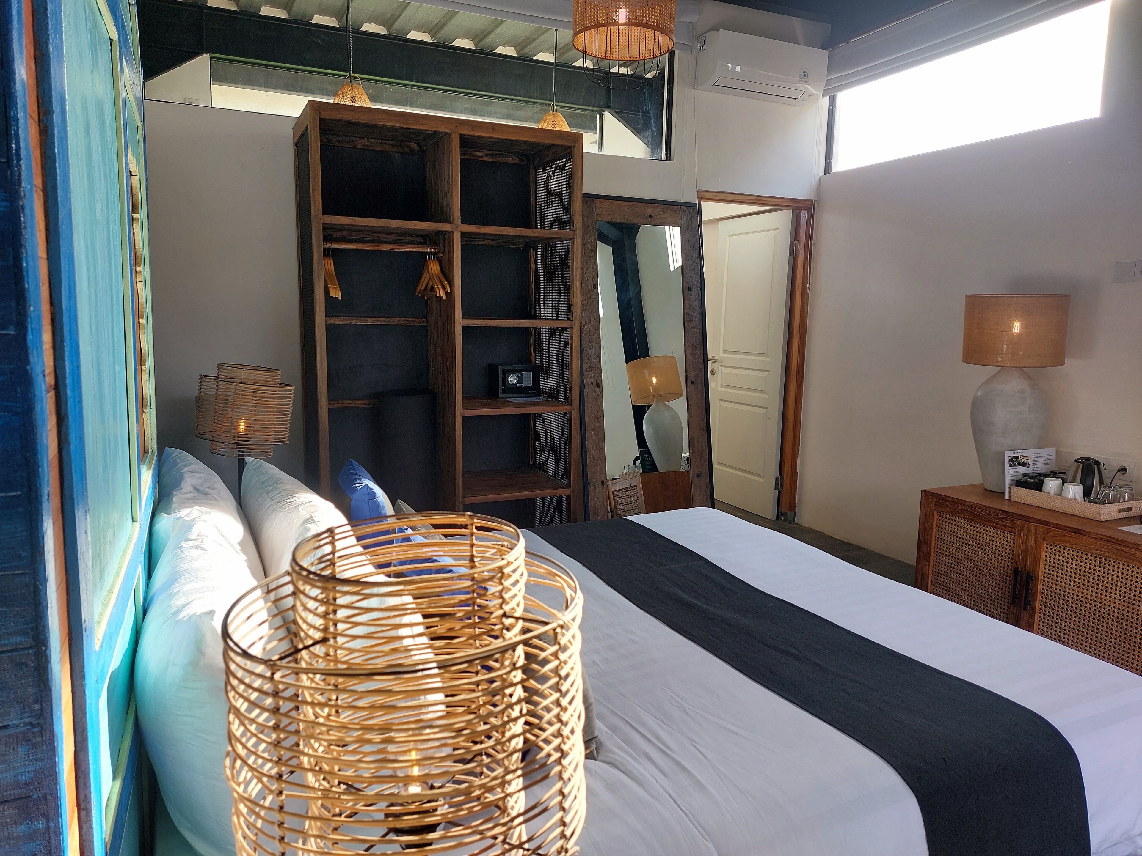 A bedroom with a large bed, a wardrobe, a mirror, and a bedside table with a lamp.