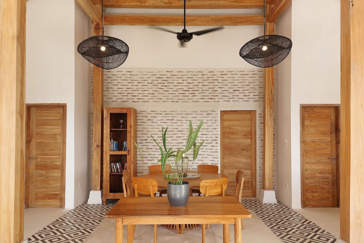 A dining area with a wooden table and chairs, a bookshelf, and a patterned floor.