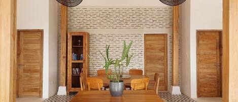 A dining area with a wooden table and chairs, a bookshelf, and a patterned floor.