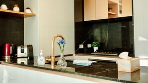 A modern kitchen with a marble countertop, a gold faucet, a vase with flowers, a coffee maker, and a tissue box. - New Year eve’s Fireworks & BayView Apt in CBD (Melbourne)