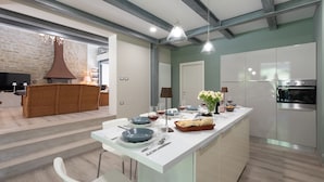Eine moderne Küche mit einer zentralen Kochinsel, weißen Schränken und einem eingebauten Backofen.