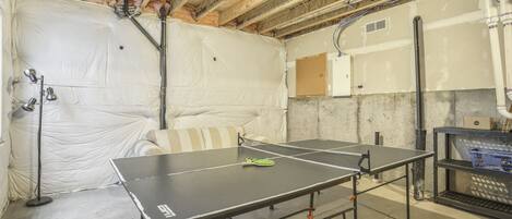 A room with two ping pong tables, a couch, and a concrete floor.