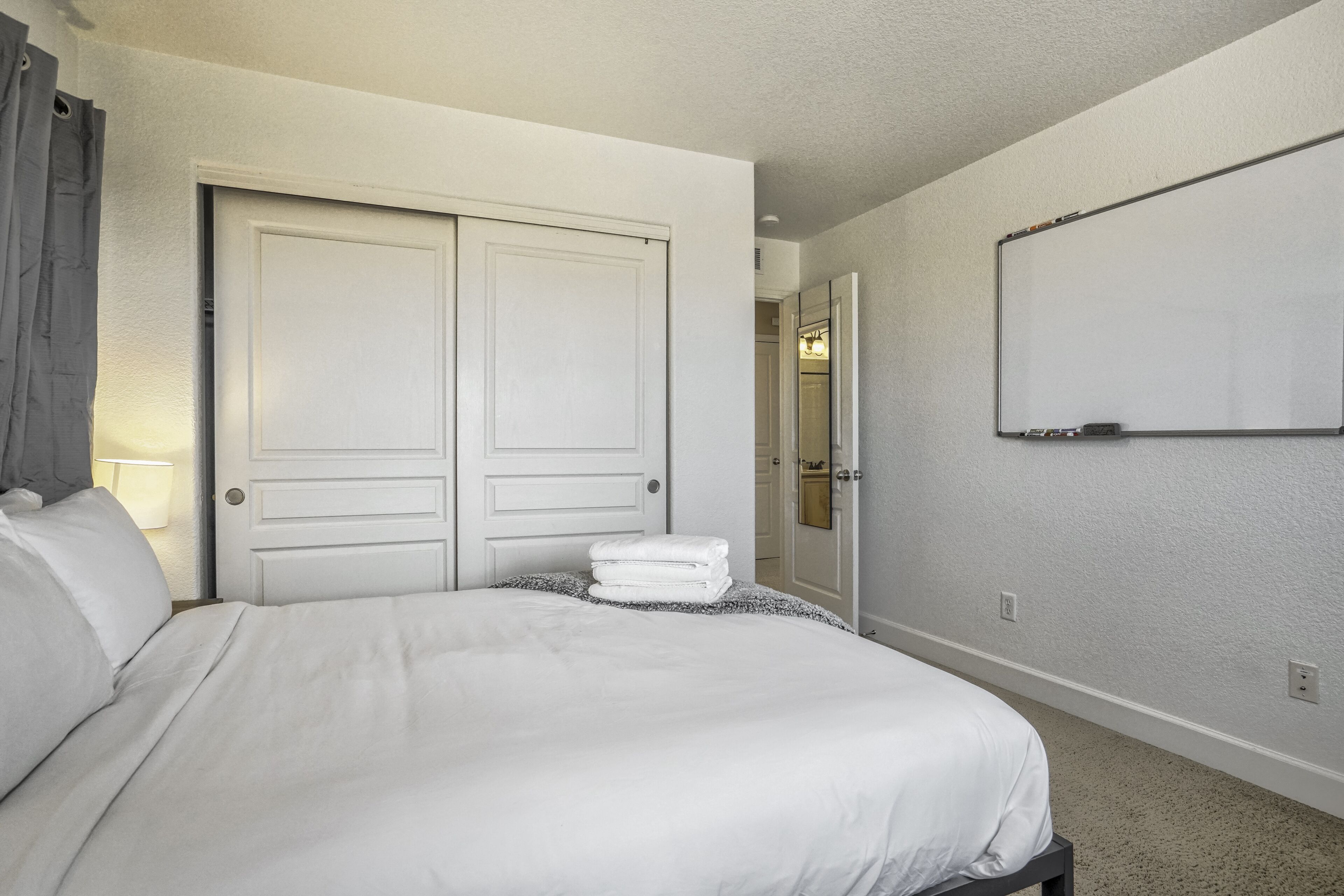 Ein Hotelzimmer mit einem großen Bett, einem Schrank und einem an der Wand befestigten Fernseher.