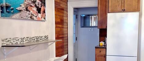 A modern kitchen with wooden cabinets, a built-in refrigerator, and a bar area with stools.