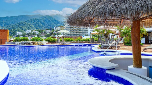 A swimming pool with a thatched roof structure, surrounded by lounge chairs and a mountainous backdrop. - Serene Paradise: Casa Leone 3 in Selva Romántica! 2BD Condo for rent in Old Tow (Puerto Vallarta)